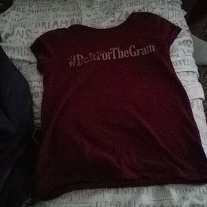 A burgundy, shirt  with gold printed letters